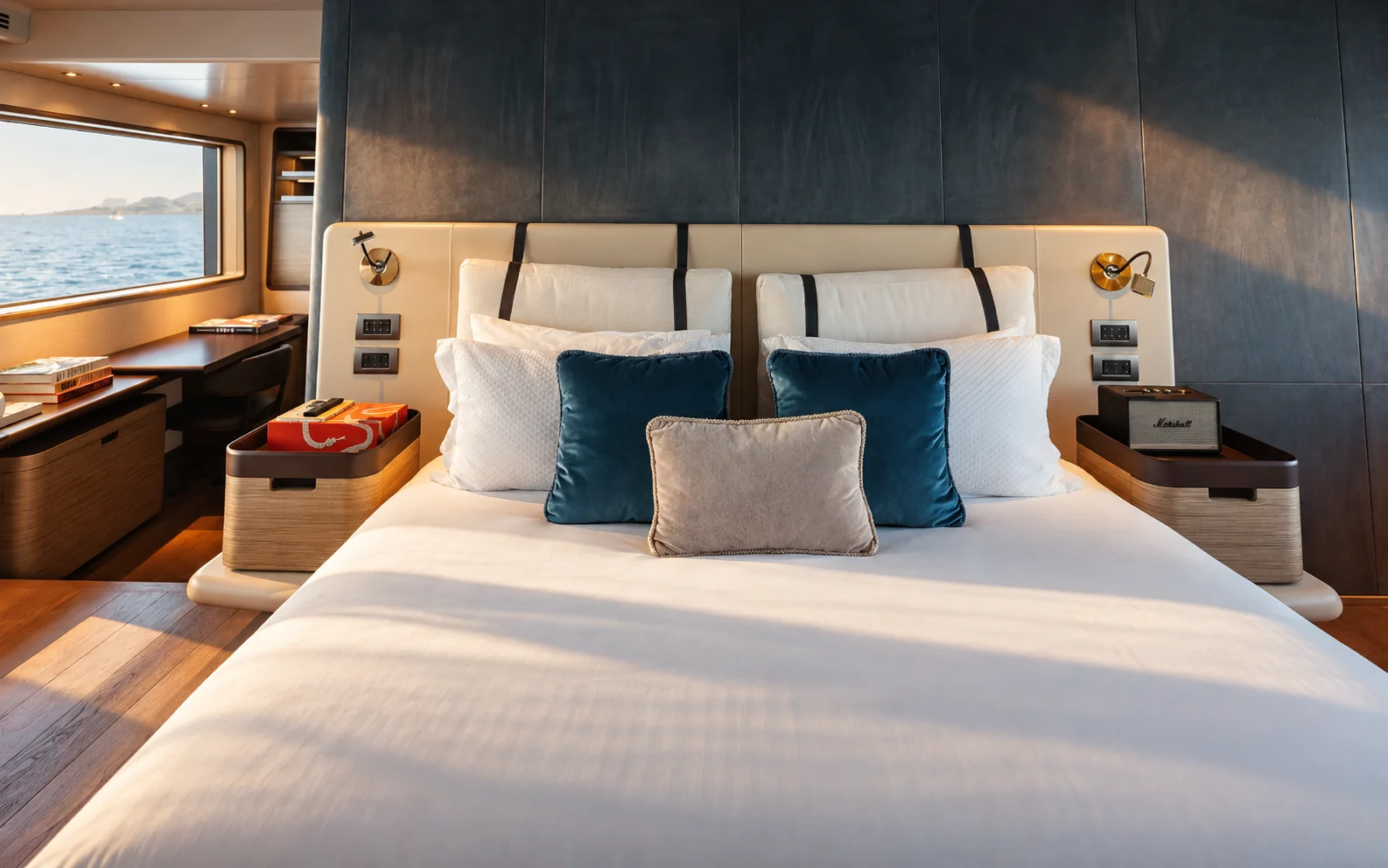 The owner's bed, with blue cushions, walnut furniture and a sea view.