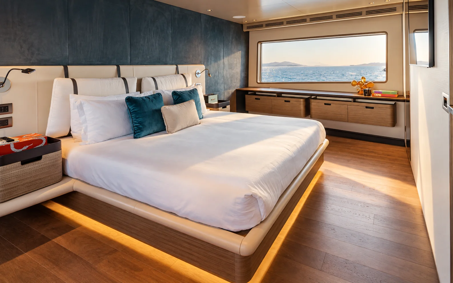 The owner's suite, with a wide bed and walnut cabinetry beneath the sea-facing window.